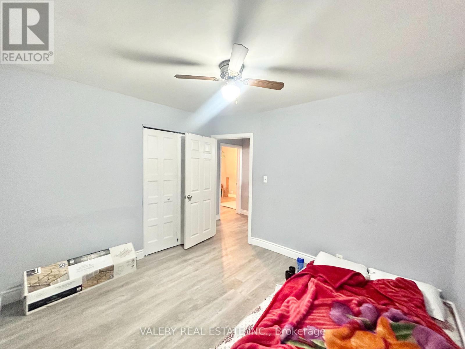 A bedroom with a bed covered in a colorful blanket and a ceiling fan.