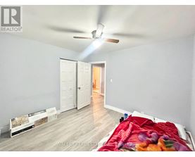 A bedroom with a bed covered in a colorful blanket and a ceiling fan.