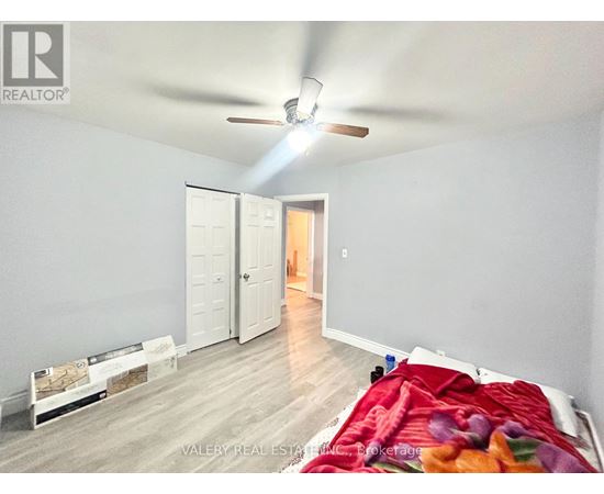 A bedroom with a bed covered in a colorful blanket and a ceiling fan.