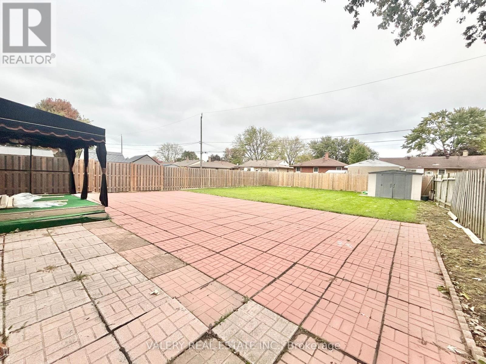 A backyard with a brick patio and a pool table.