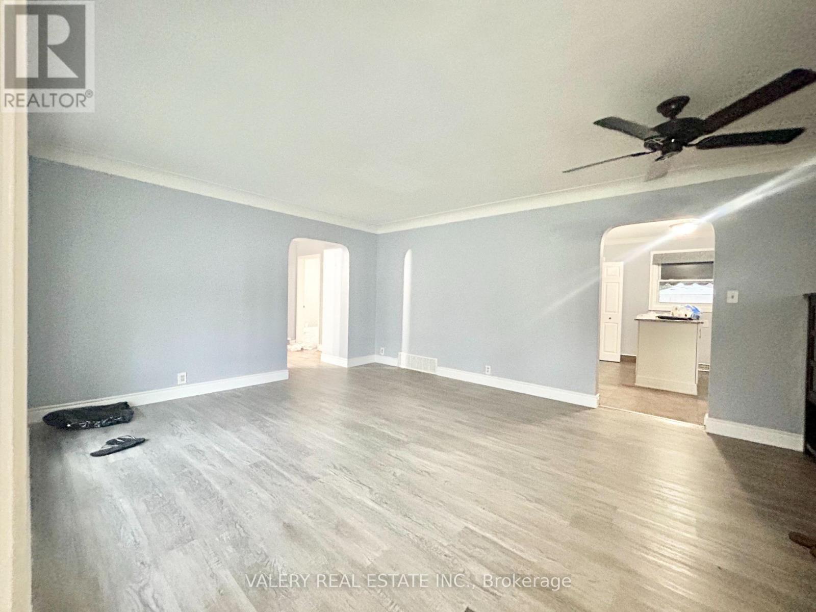 A spacious room with a ceiling fan and light wood flooring.