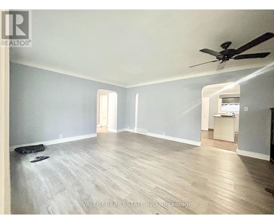 A spacious room with a ceiling fan and light wood flooring.