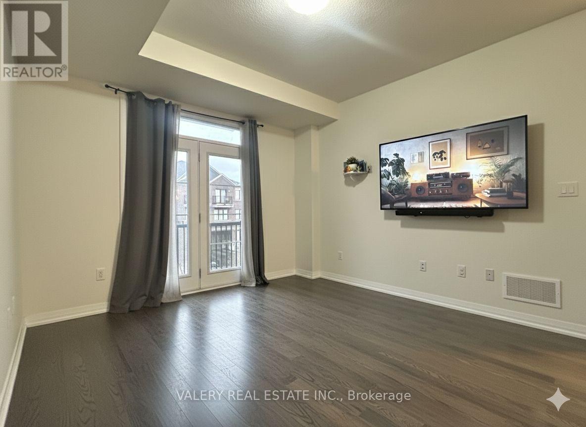 A living room with a flat screen TV mounted on the wall and a sliding glass door leading to a balcony.