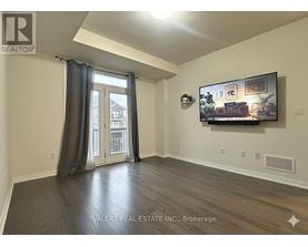 A living room with a flat screen TV mounted on the wall and a sliding glass door leading to a balcony.