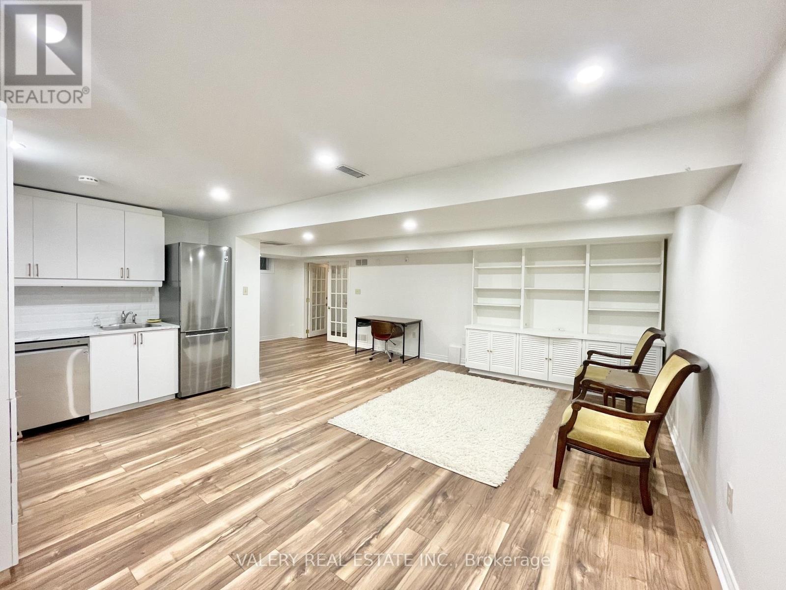 A spacious kitchen with white cabinets and a wooden floor.
