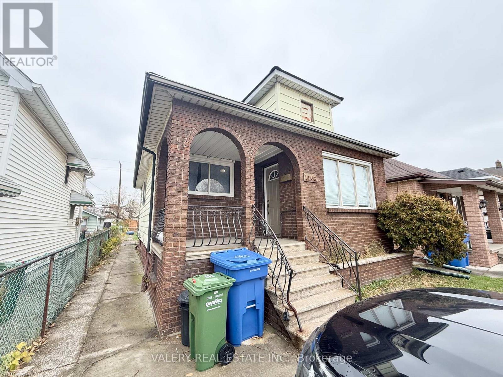 A house with a brick facade and a car parked in front.