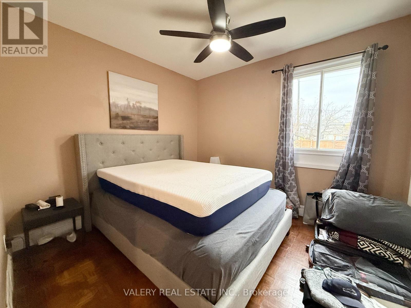 A bedroom with a bed, a ceiling fan, and a window with curtains.