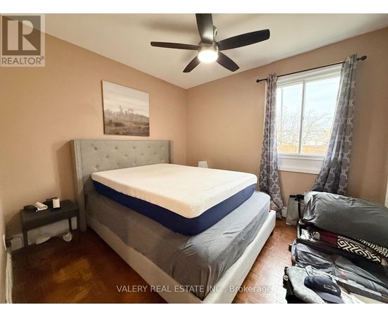 A bedroom with a bed, a ceiling fan, and a window with curtains.