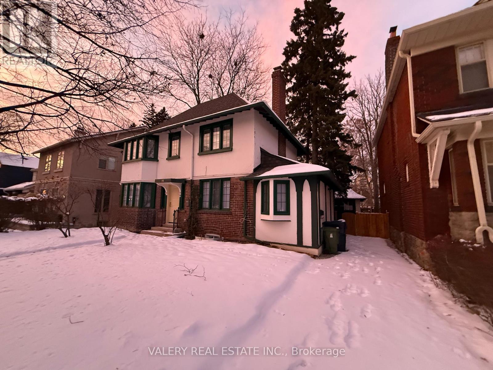 A house with a snowy front yard and a tree in the background.