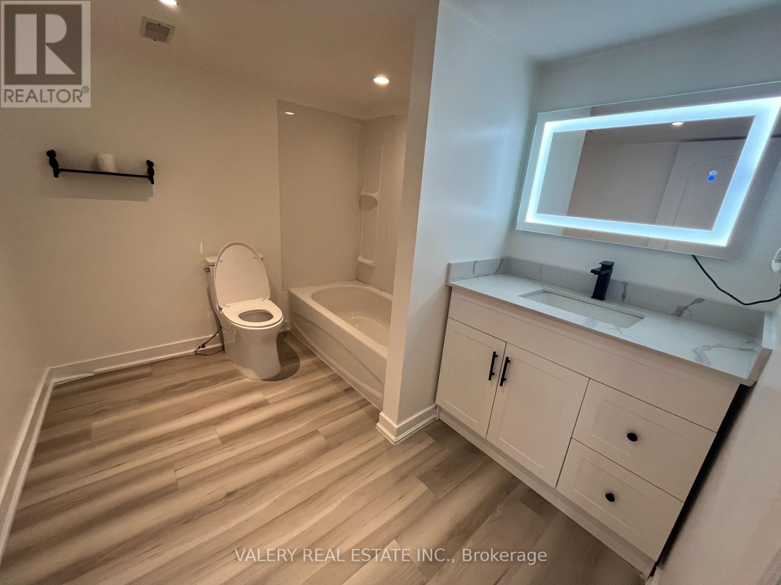 A bathroom with a toilet, sink, and mirror.