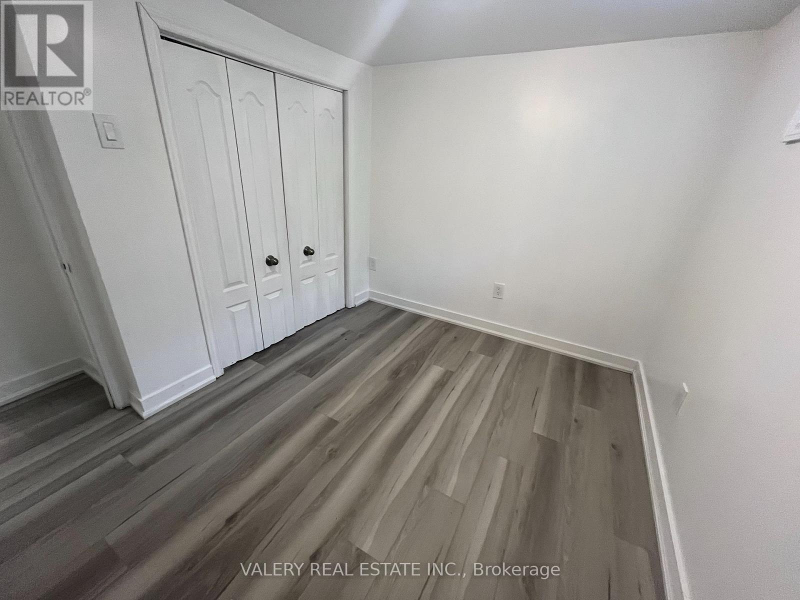 A room with wood flooring and white walls.