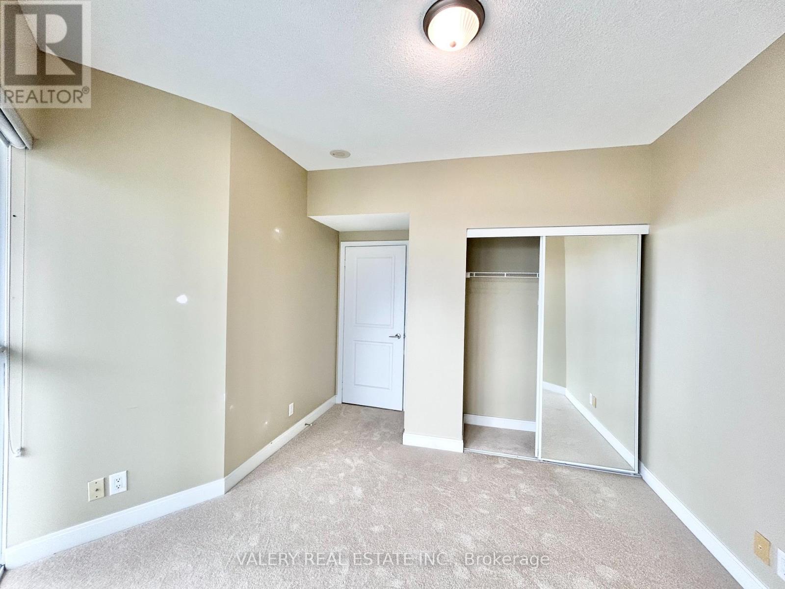 A bedroom with a white door and carpeted floor.
