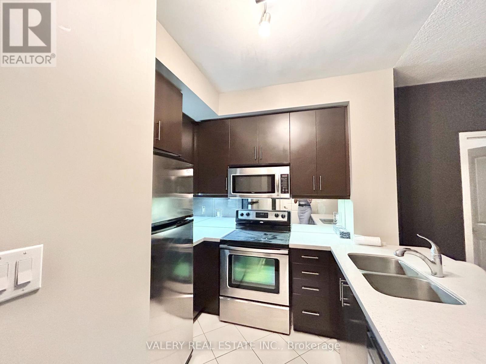 A kitchen with dark brown cabinets and stainless steel appliances.