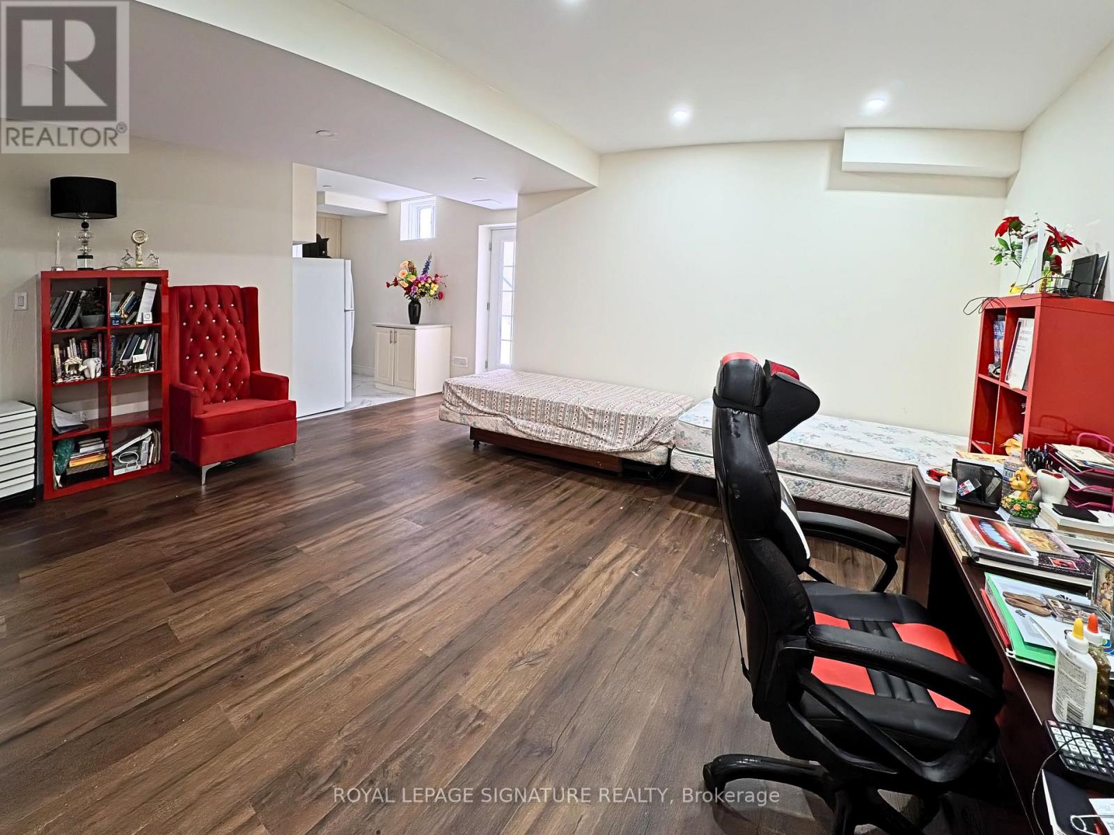 A room with a red chair and a desk with a laptop on it.