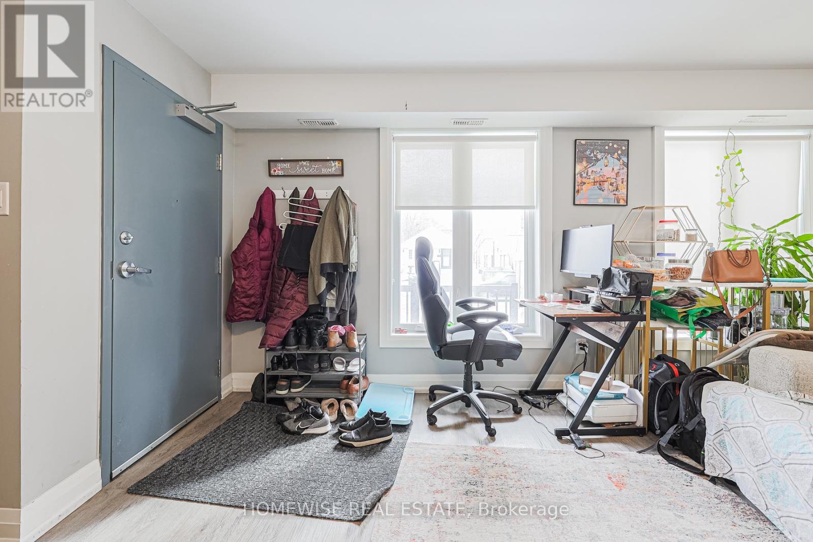 A room with a blue door, a desk with a computer, and a chair.