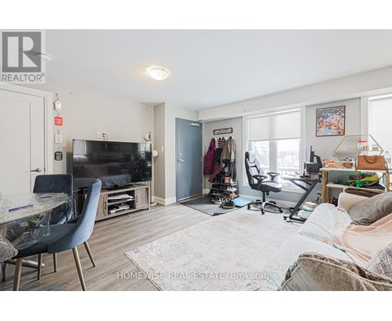 A living room with a blue chair and a cluttered bed.