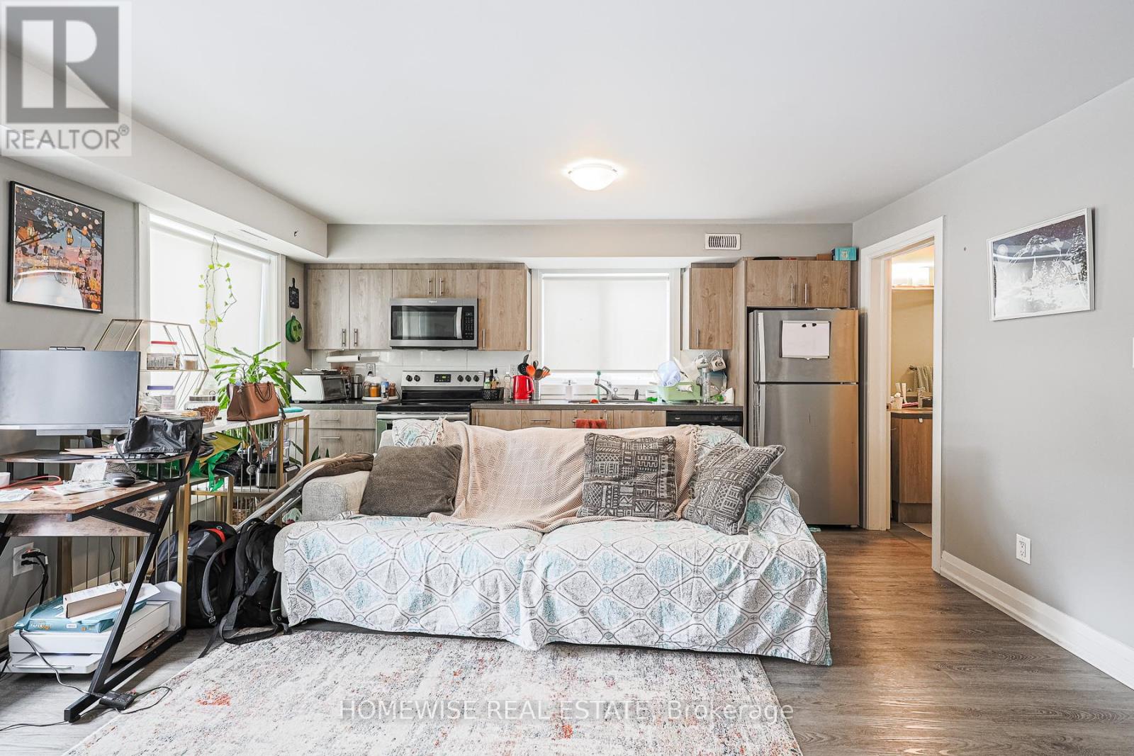 A bedroom with a bed and a kitchen area in the background.