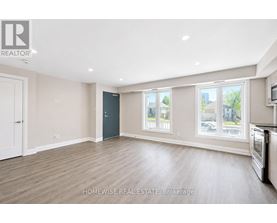 A bedroom with a bed and a kitchen area in the background.