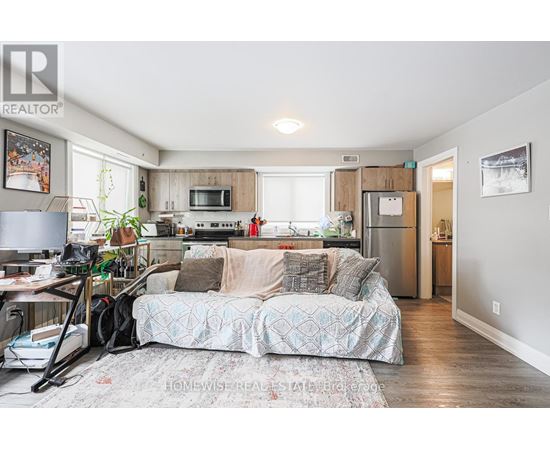A bedroom with a bed and a kitchen area in the background.