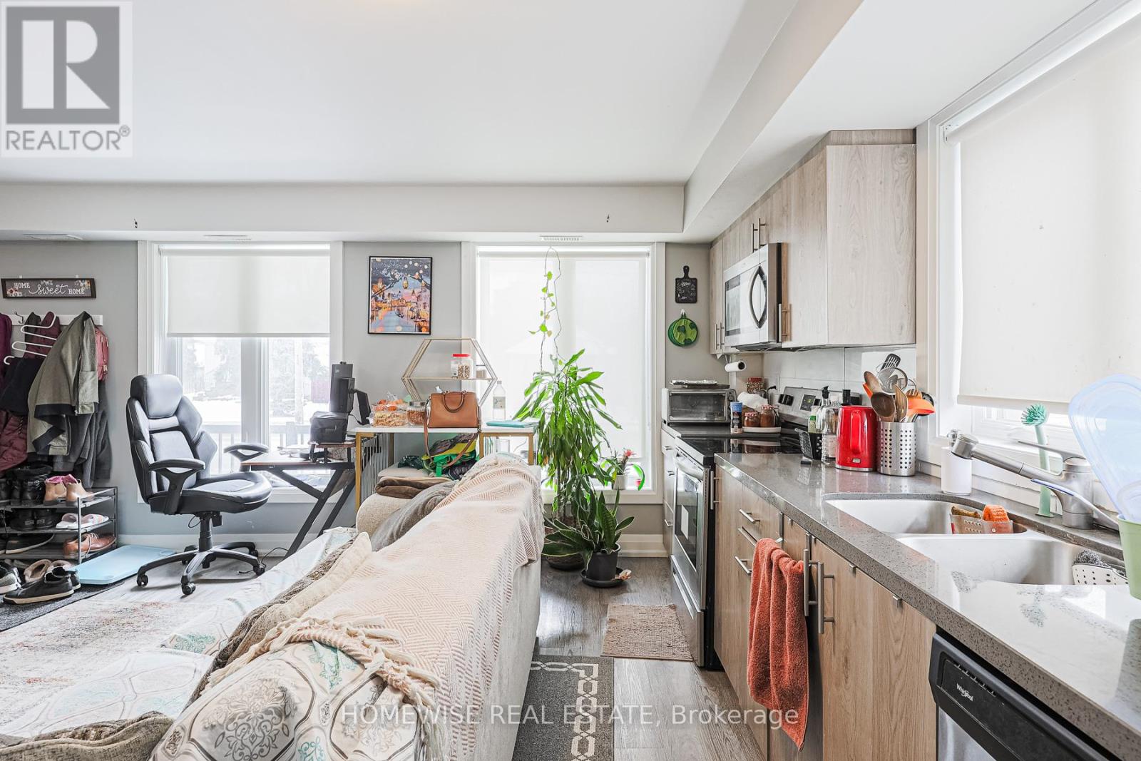 A kitchen with a sink, a couch, and a desk with a chair.