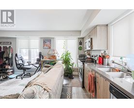 A kitchen with a sink, a couch, and a desk with a chair.