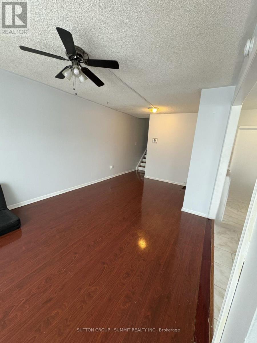 A room with a ceiling fan and wooden flooring.