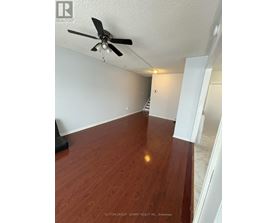 A room with a ceiling fan and wooden flooring.