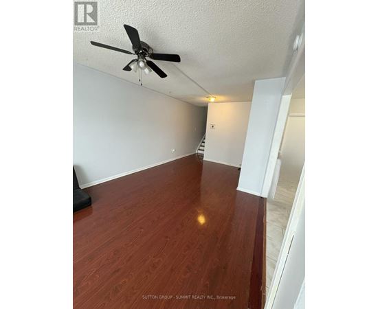 A room with a ceiling fan and wooden flooring.