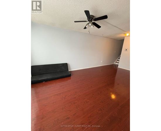 A room with a ceiling fan and a black couch.