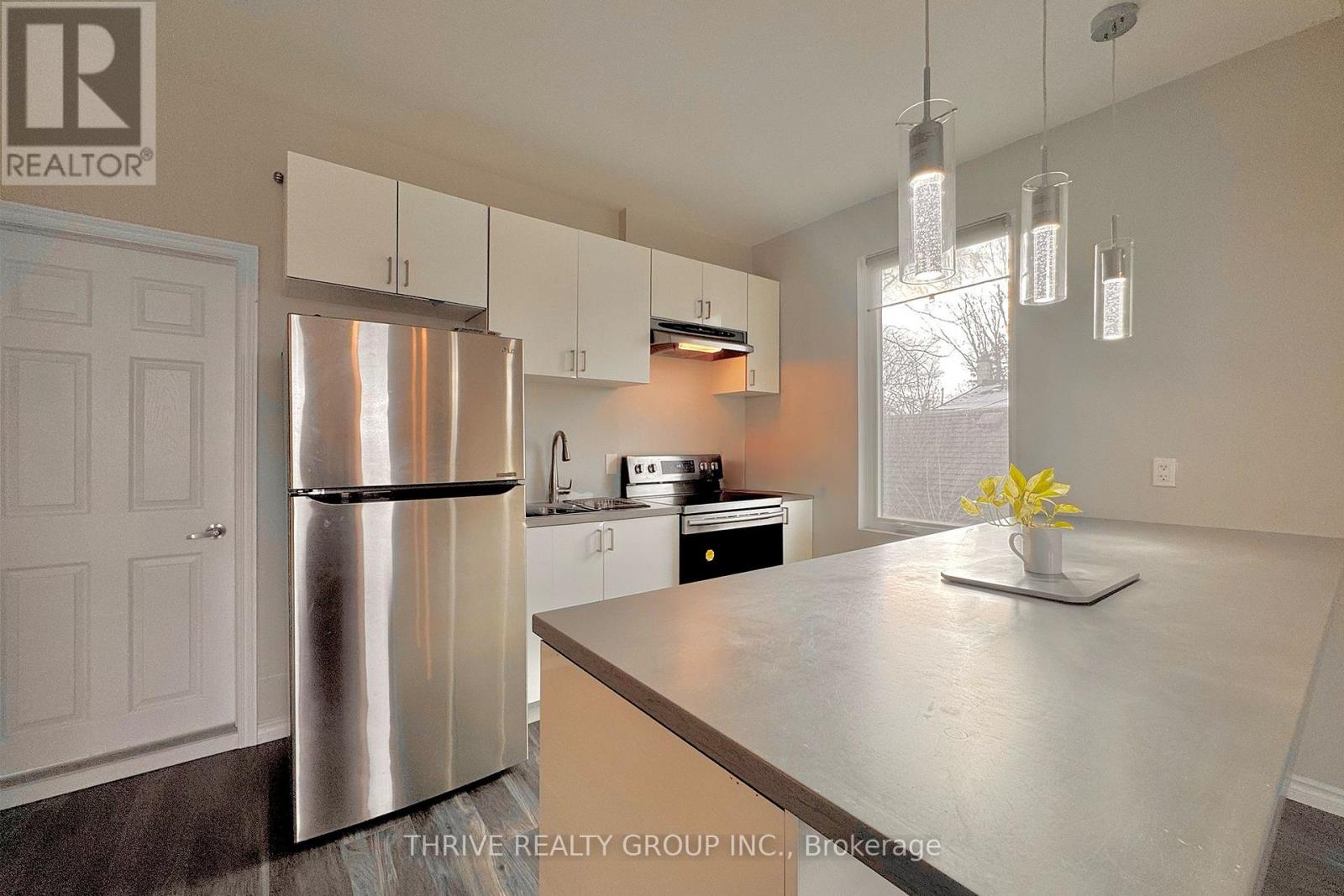 A kitchen with a stainless steel refrigerator and a countertop with a vase of flowers on it.