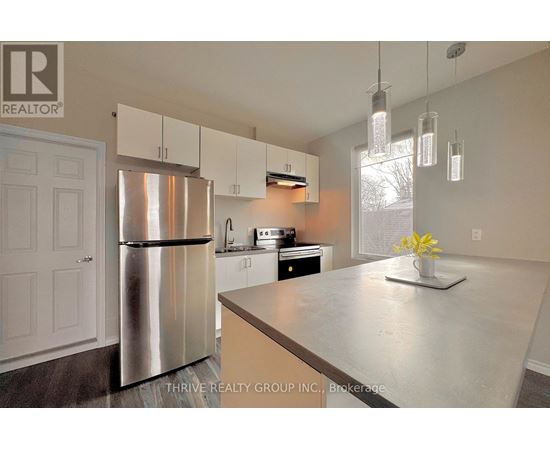 A kitchen with a stainless steel refrigerator and a countertop with a vase of flowers on it.