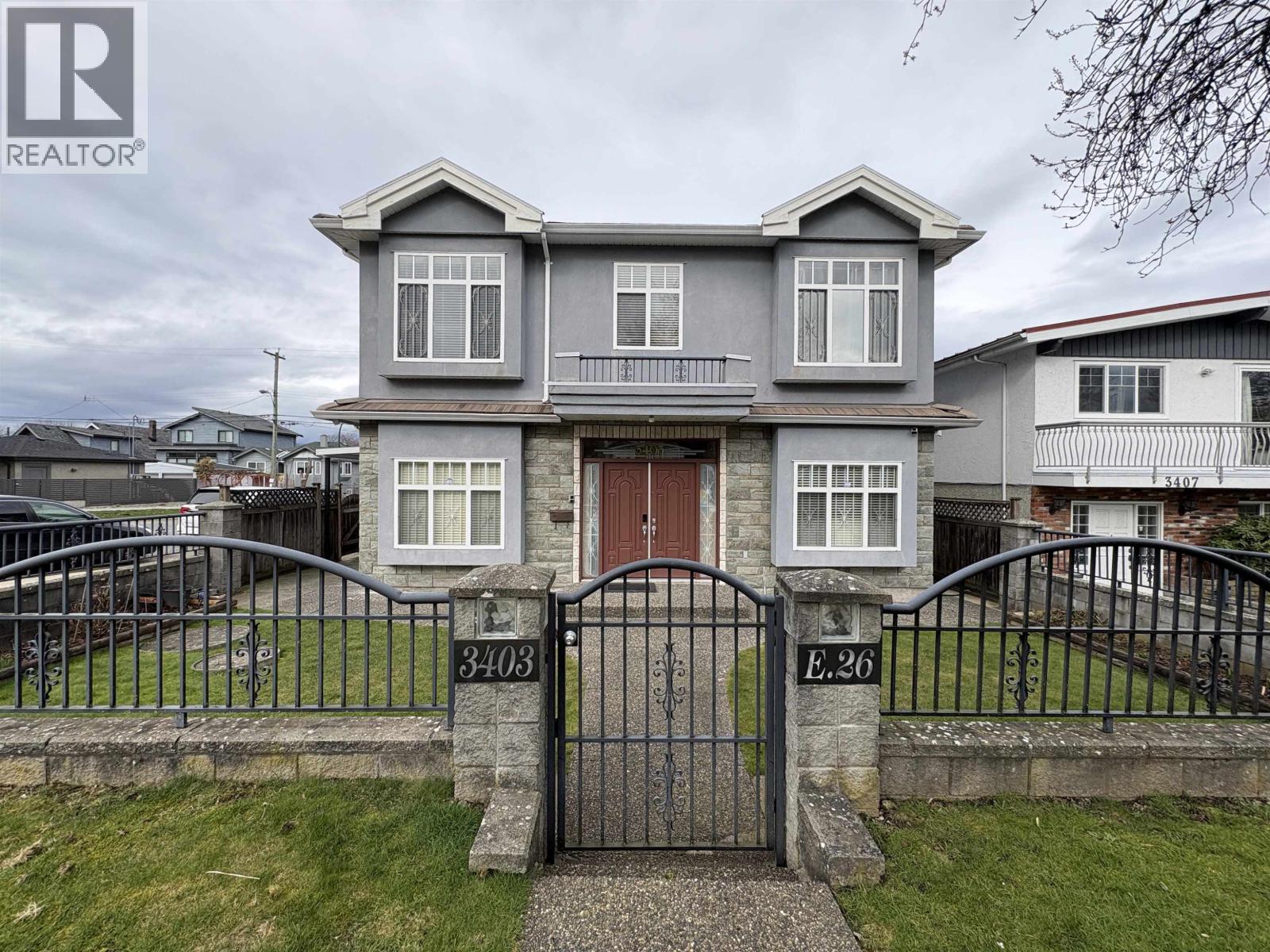 A grey house with a black gate in front.