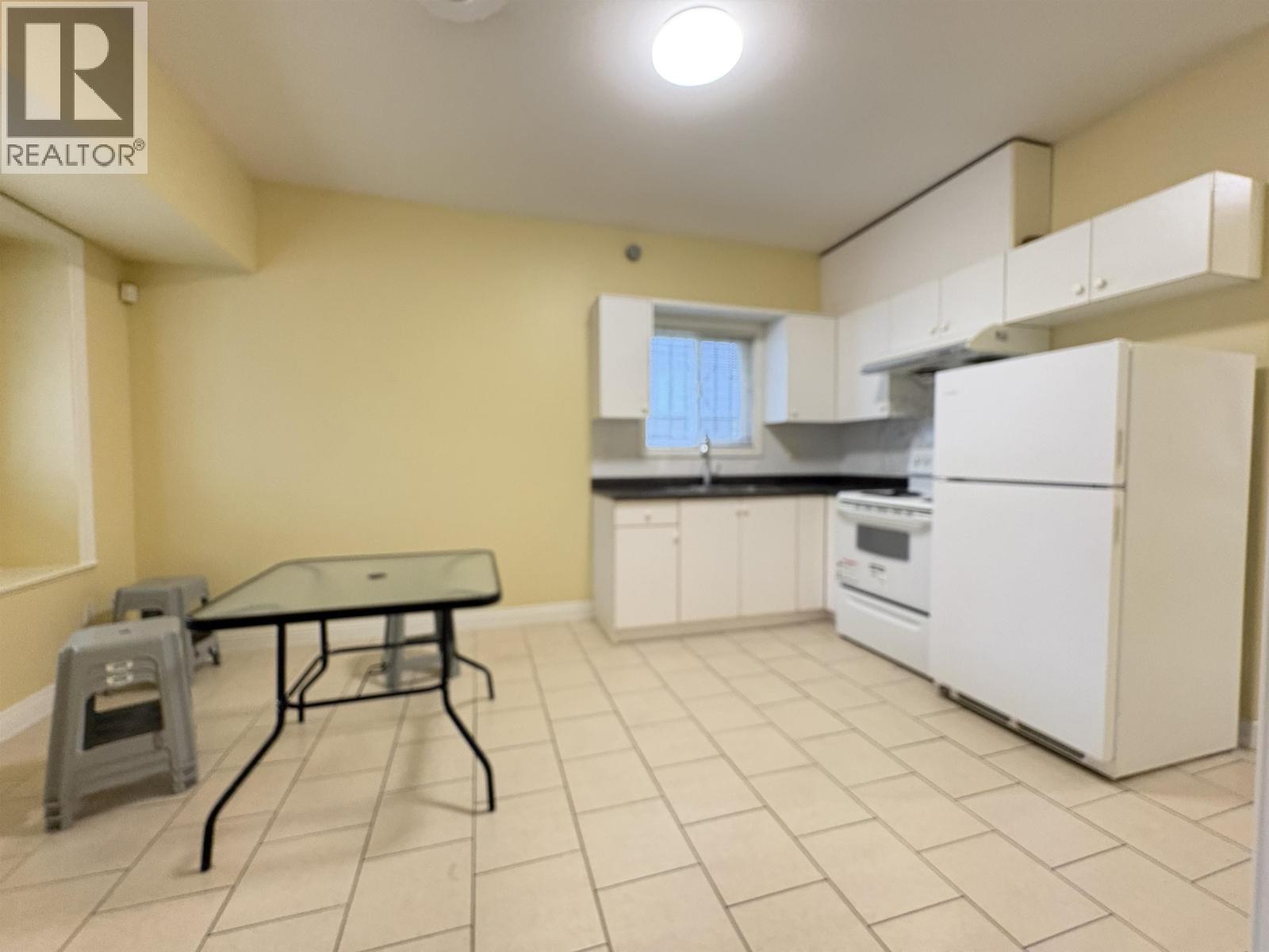 A kitchen with a table and chairs in the foreground and a refrigerator in the background.