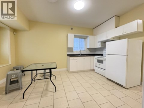 A kitchen with a table and chairs in the foreground and a refrigerator in the background.