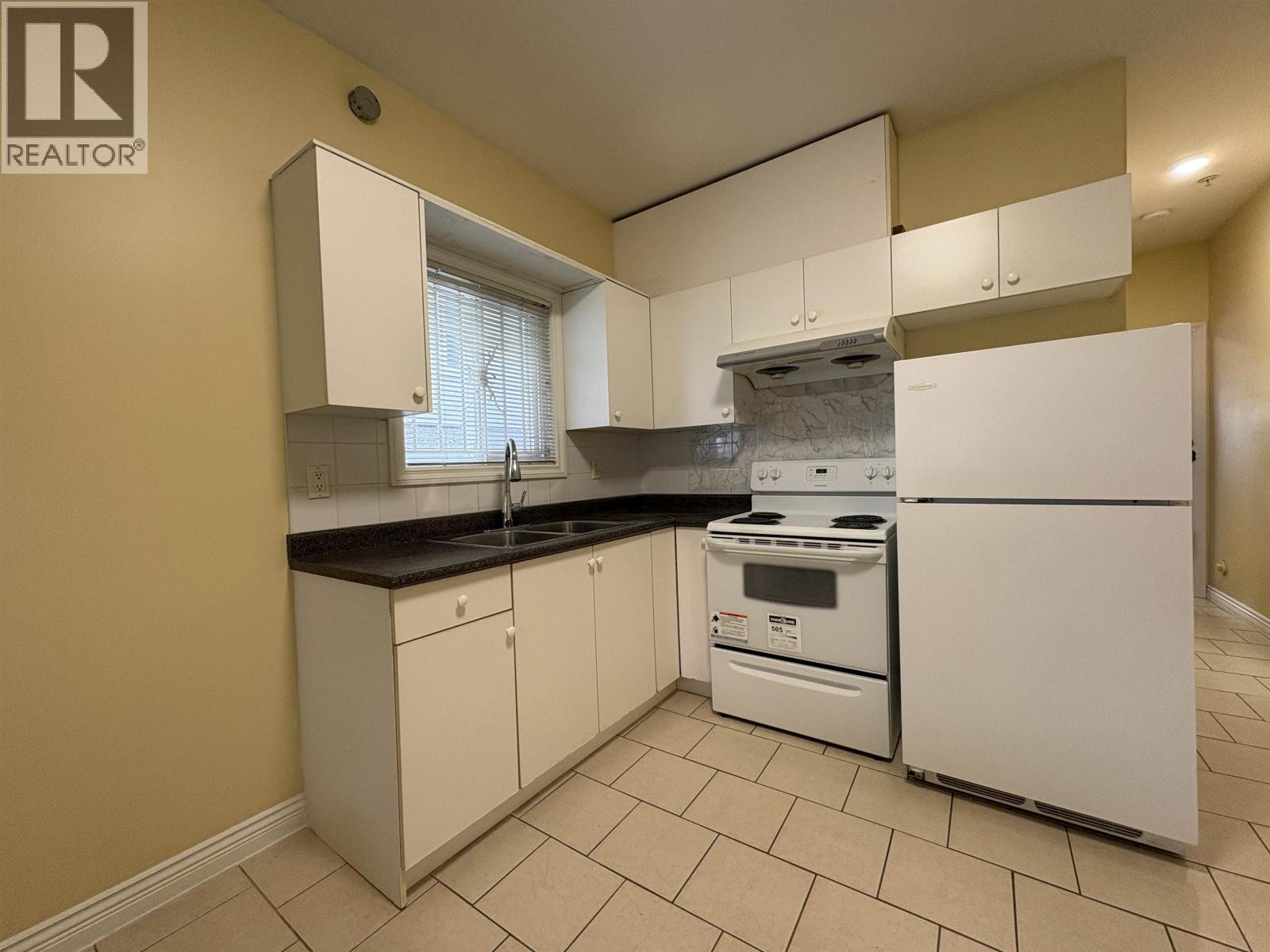 A kitchen with white appliances and cabinets.