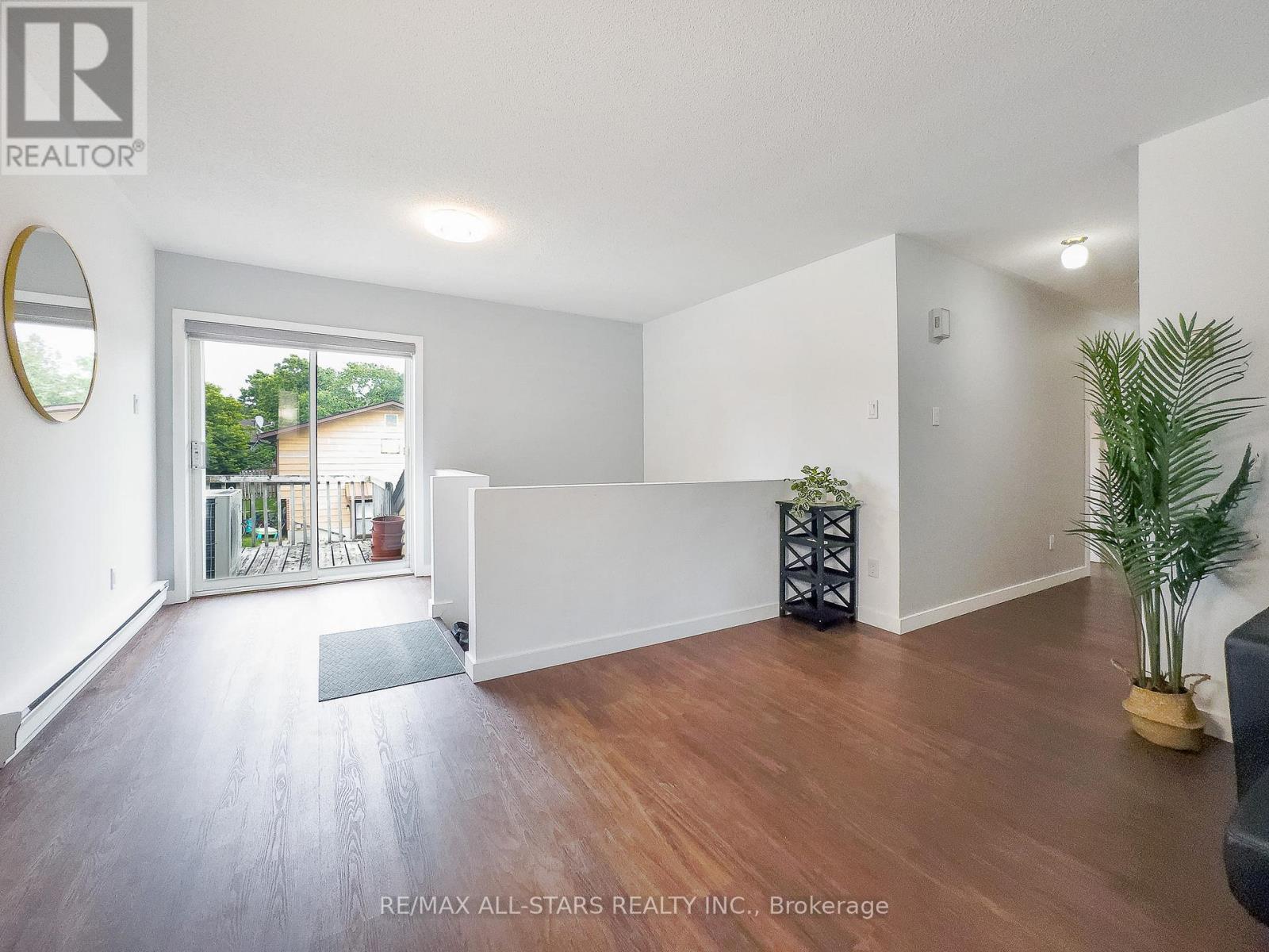 A spacious room with wooden flooring and a large mirror on the wall.