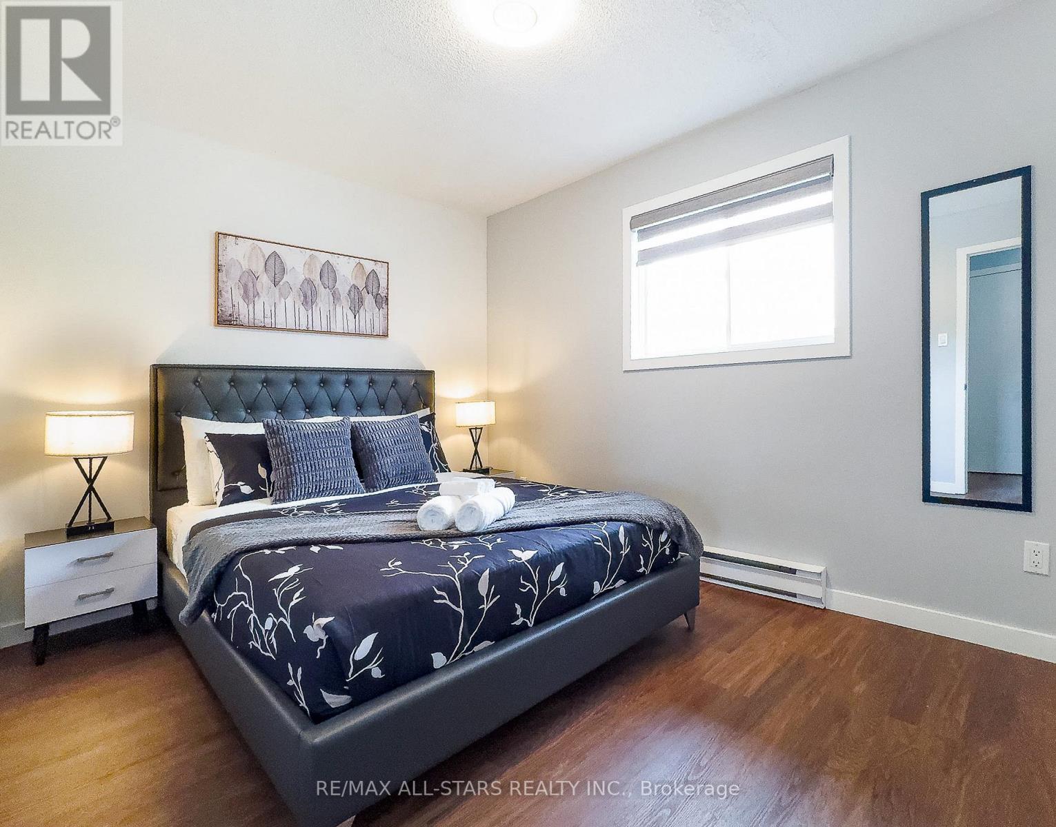 A bedroom with a large bed and a painting on the wall.
