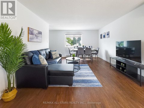 A living room with a black couch and a wooden floor.