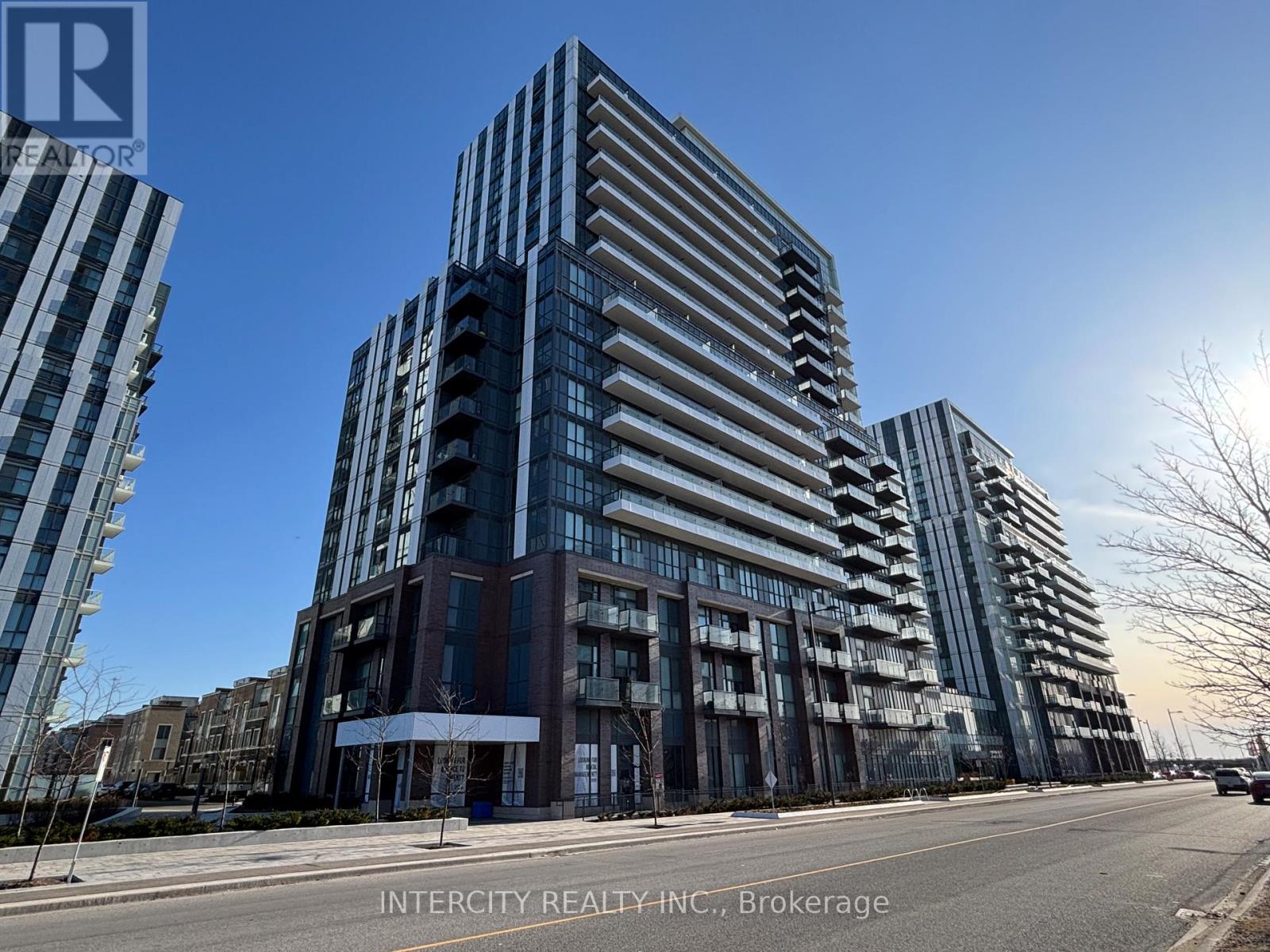 A tall building with a glass facade stands in front of other buildings.