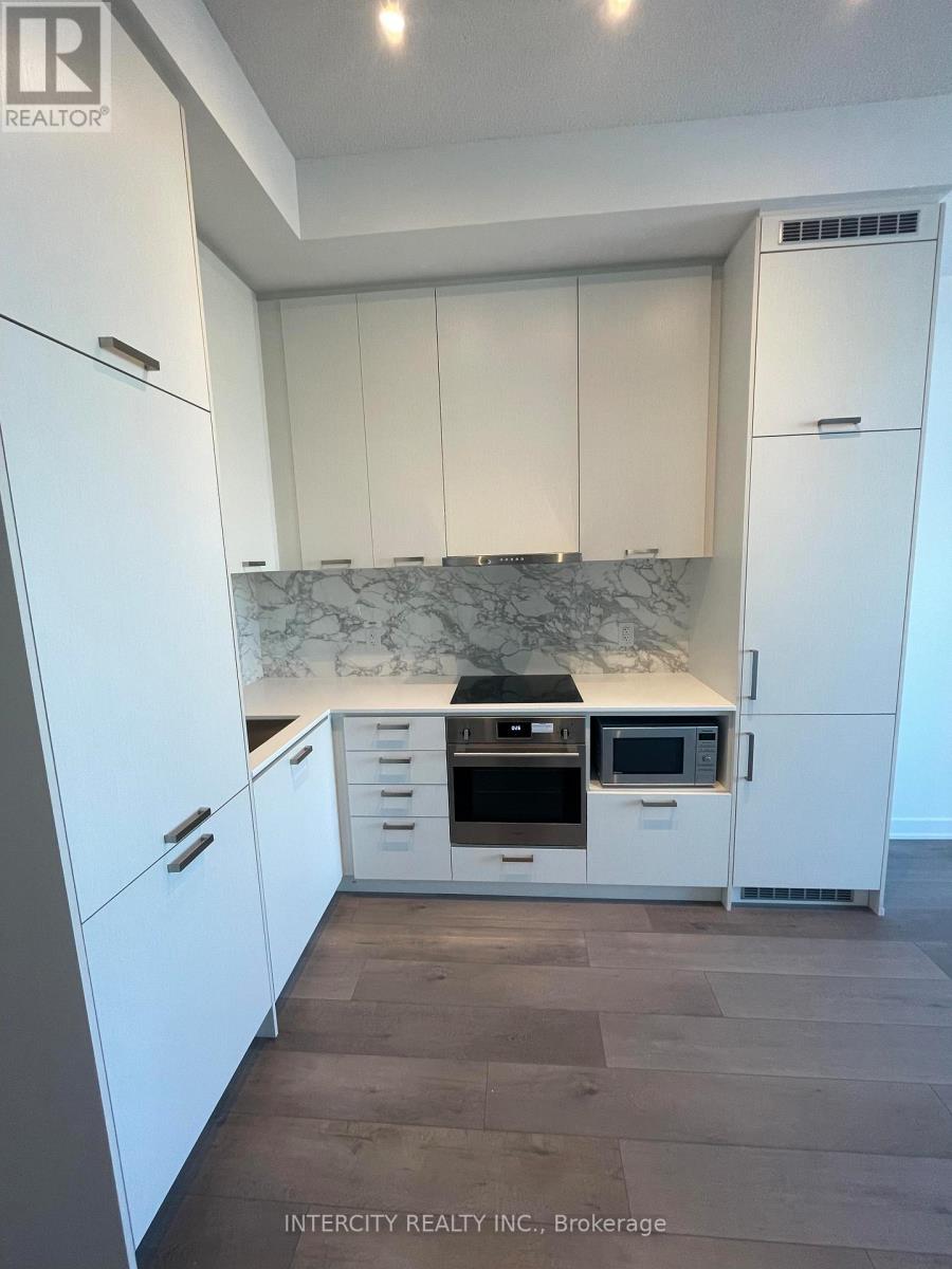 A kitchen with white cabinets and a marble backsplash.