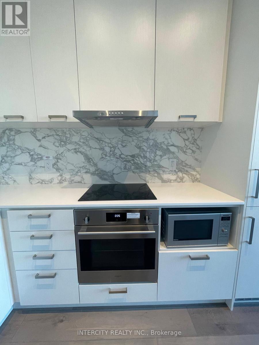 A kitchen with white cabinets and a marble countertop.