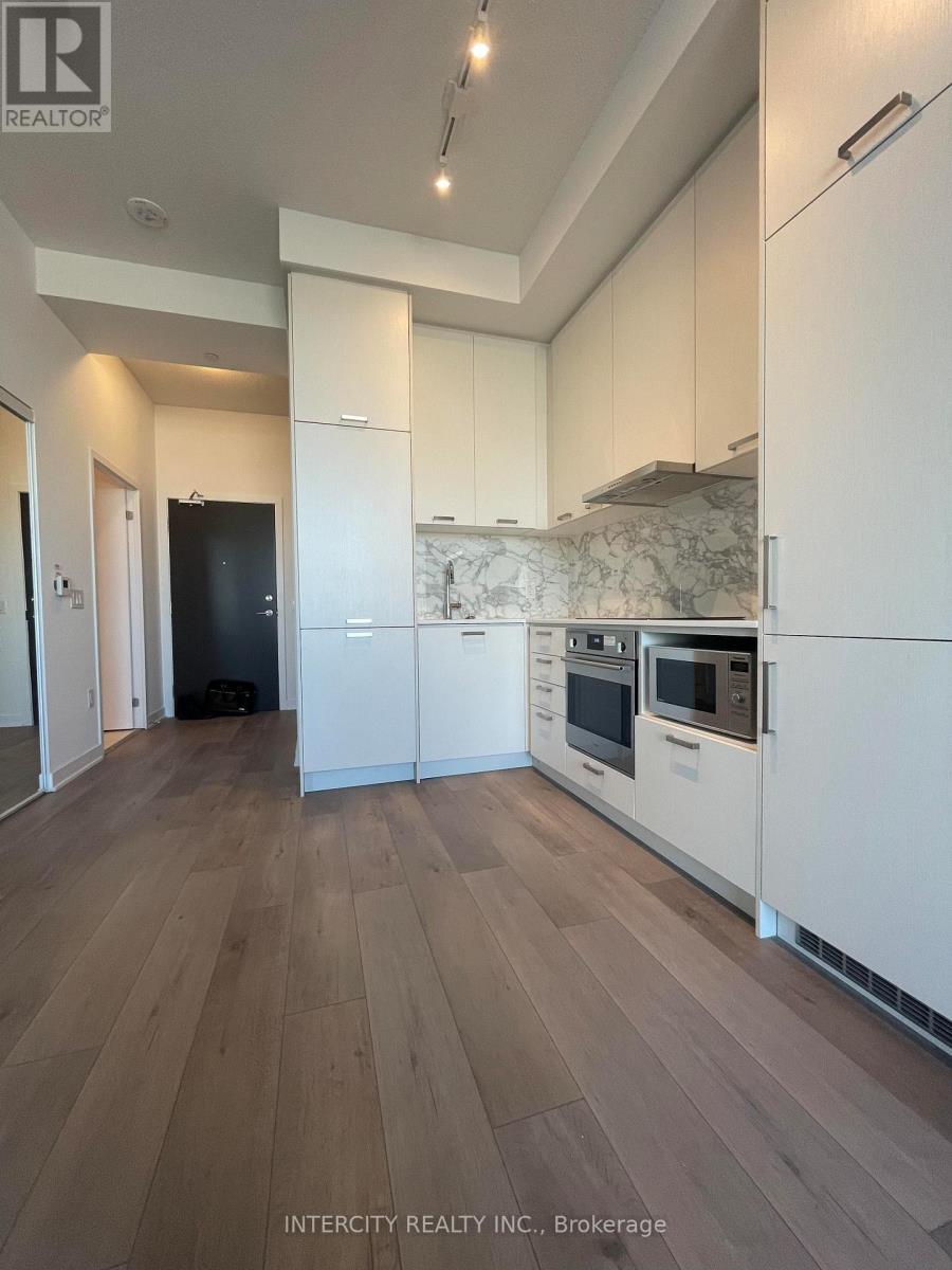A kitchen with white cabinets and a black refrigerator.