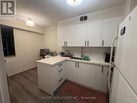 A kitchen with white cabinets and a wooden floor.