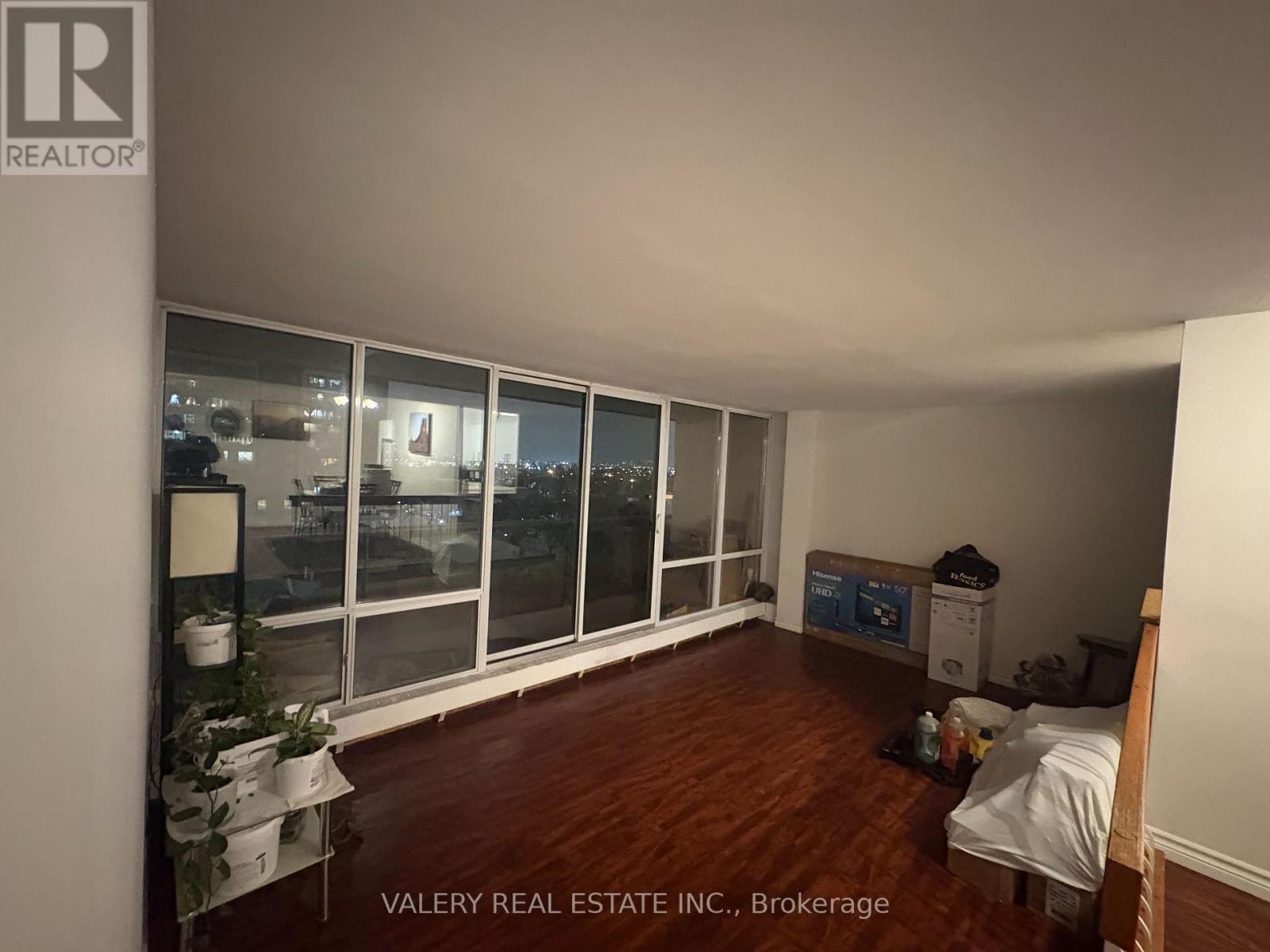 A bedroom with a bed, dresser, and window overlooking a cityscape.