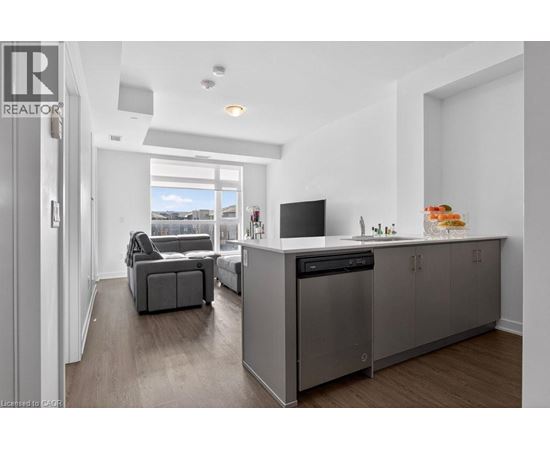 A modern kitchen with a grey cabinetry and a black fridge.