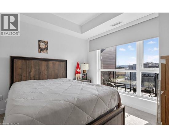 A bedroom with a large bed and a window overlooking a patio.