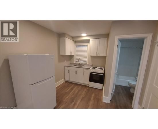 A small kitchen with a refrigerator, cabinets, and a stove top oven.