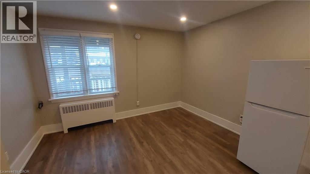 A room with a white refrigerator and a window with blinds.