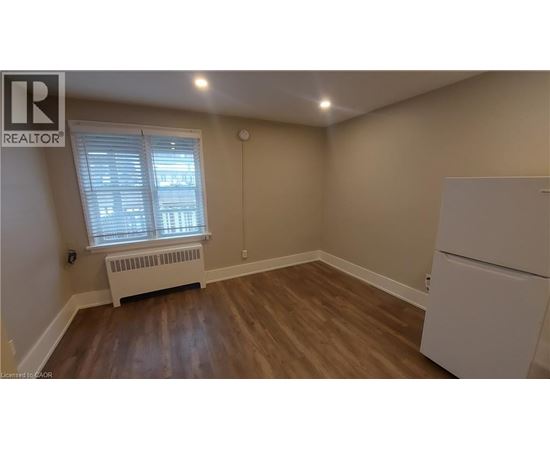 A room with a white refrigerator and a window with blinds.