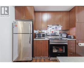 A kitchen with wooden cabinets and a stainless steel refrigerator.